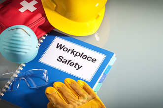 Workplace safety binder surrounded by personal protective equipment