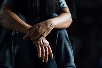Person sitting with hands and face in knees